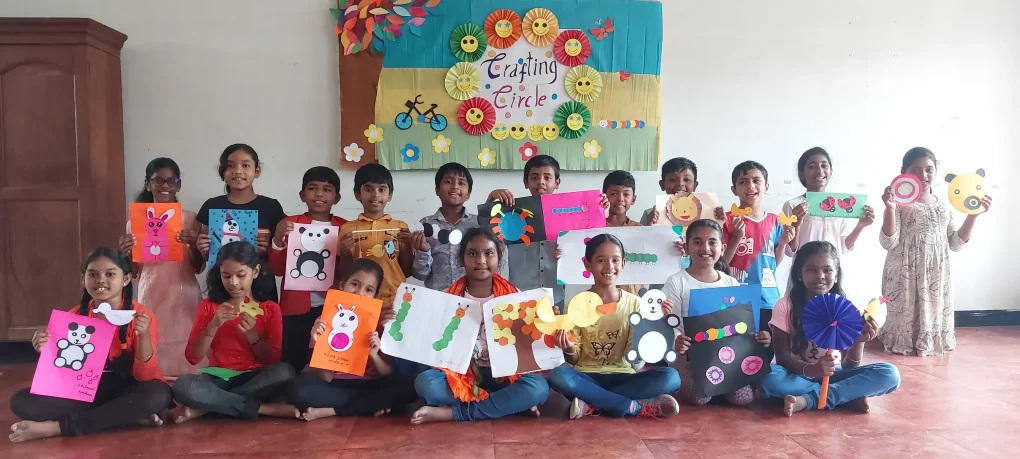A colorful notice board at Vidhya Peetham i-School decorated with students' circle crafts including snowmen and teddy bears, reflecting their learning about 'circles radius diameter.
