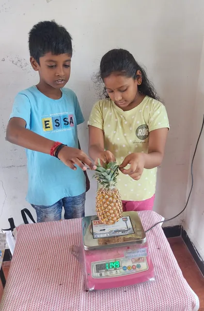 Young students taking turns to measure their weight on a human scale, understanding the concept of mass in kilograms.