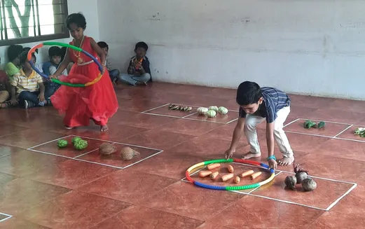 A young student from the best CBSE school in Salem demonstrates understanding of larger number groups with a hula hoop.