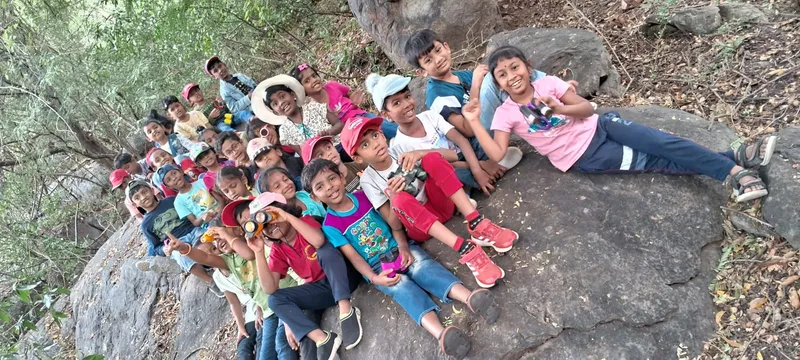 Trekking for Kids Grade 1 children from the best CBSE school in Salem sitting on rocks amidst greenery during an educational trek.