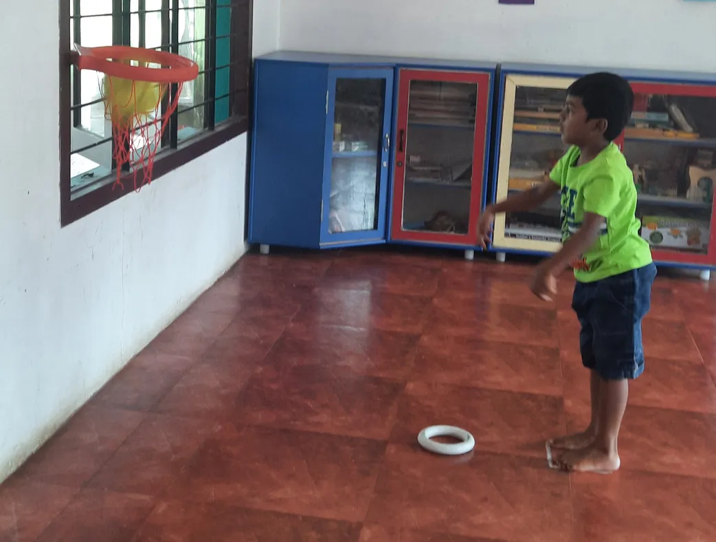 LKG Hopscotch activity 2_result A young boy focusing intently as he prepares to throw a ball into the basketball net during the hopscotch activity at a notable school in Salem.