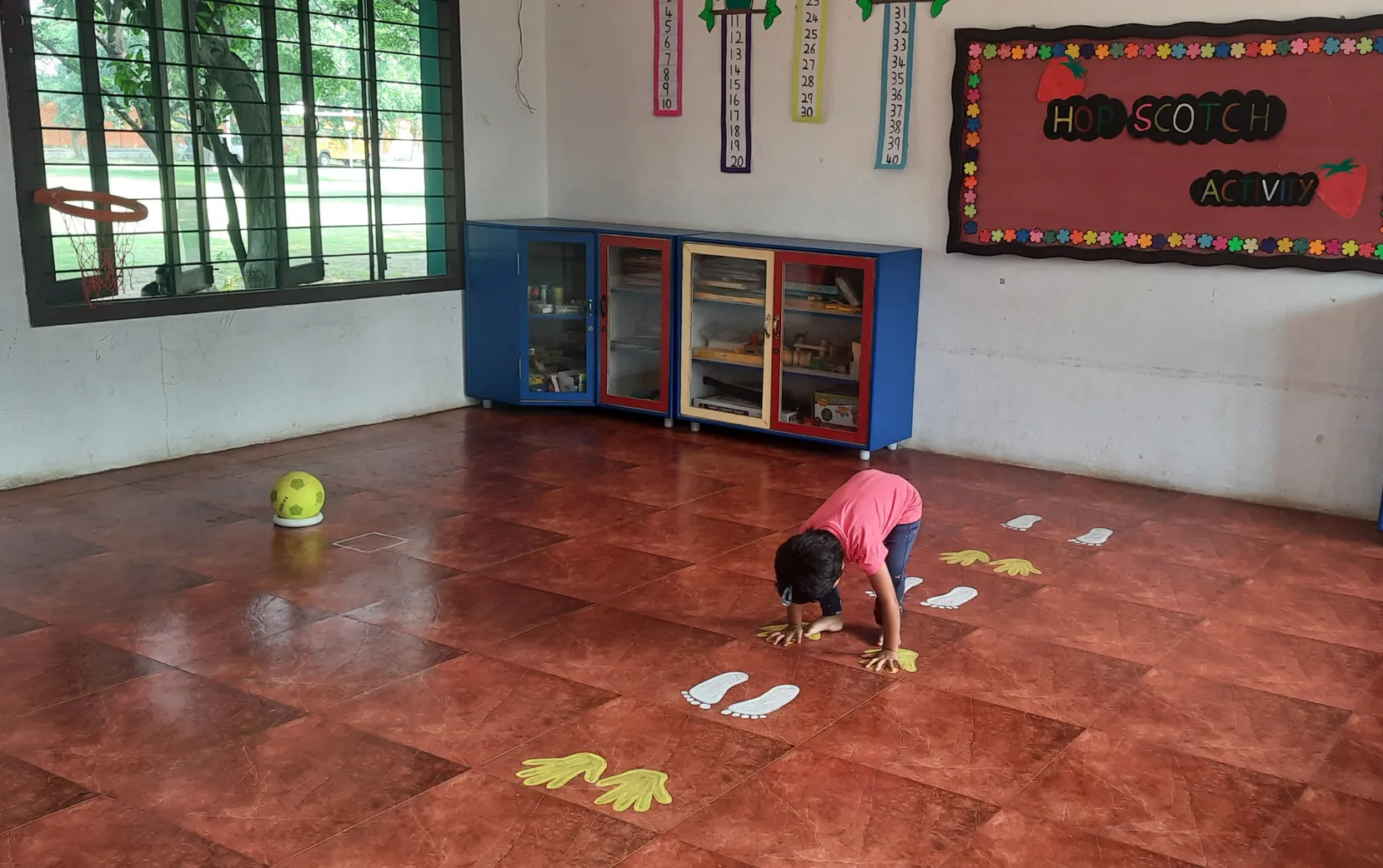 LKG Hopscotch activity 3_result Engaged child in the kindergarten hopskotch activity, matching hand and footprints on the floor, enhancing motor skills at one of the best CBSE schools in Salem.