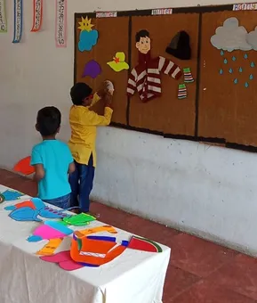 Young learners from one of the best schools in Salem, dressed in summer outfits, participate in a hands-on kindergarten seasons activity with paper cutouts.