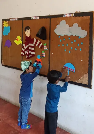 Children at a top CBSE school in Salem, Vidhya Peetham i-School, decorate a notice board with rainy season elements, showcasing their understanding of seasons.