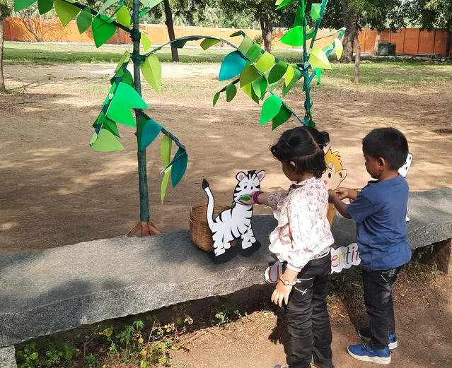 Young learners at the best CBSE school in Salem participating in a phonics game, placing paper leaves on a zebra chart during an outdoor educational activity.