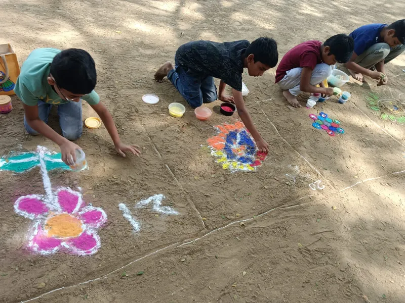 Students engaged in making vibrant Rangoli using colored powders, demonstrating teamwork and attention to detail.