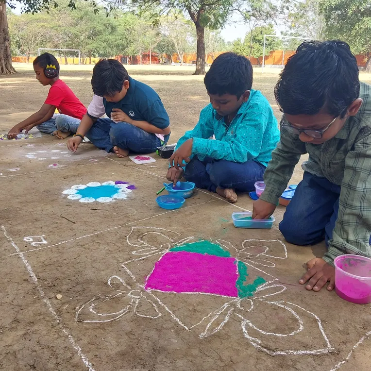 Boys in blue shirts creating colorful Rangoli designs on the ground at Vidhya Peetham i-School, showcasing creativity and cultural heritage.
2. 