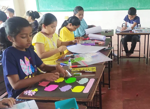 Focused second graders at Vidhya Peetham i-School engaging in a poster making activity, surrounded by colorful craft materials.