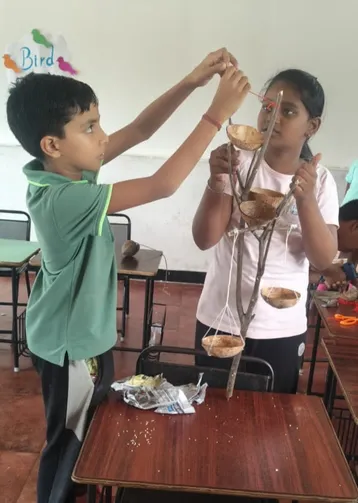 Close-up of a student at Vidhya Peetham i-School attaching a bird feeder made from a coconut shell.
