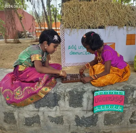 Two girls playing Pallankuzhi, a traditional Tamil game.