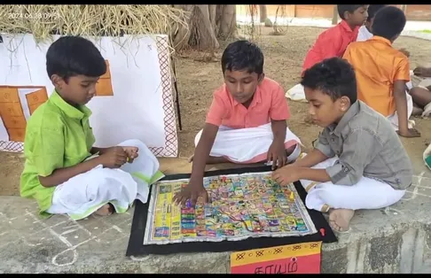 Three boys playing Thaayam, a traditional Tamil game.