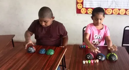Two young students painting coconut shells during an art activity at a Salem school.