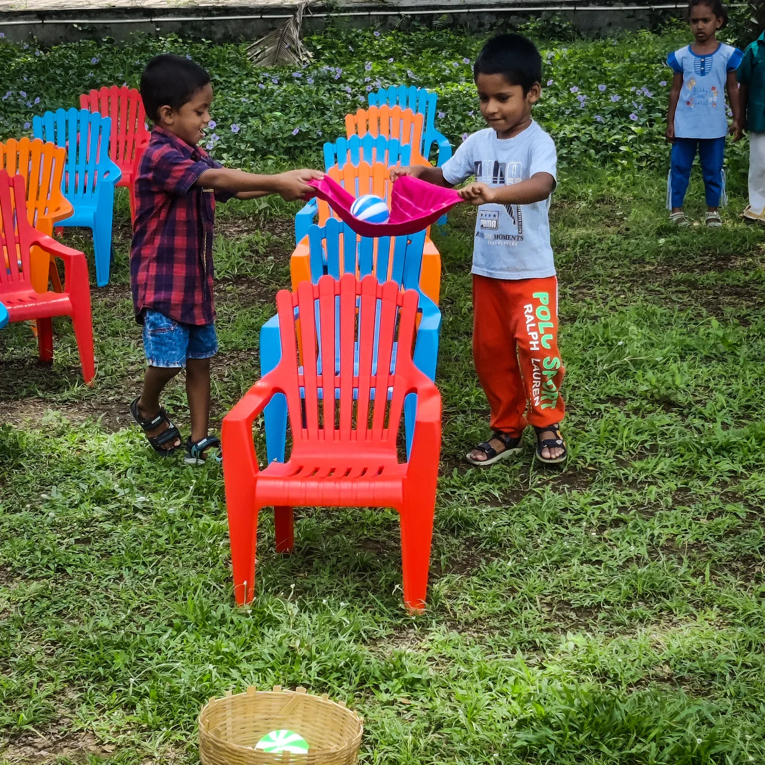 Children at Vidhya Peetham i-School focusing on balancing a ball on a towel during their outdoor gross motor skills activity.