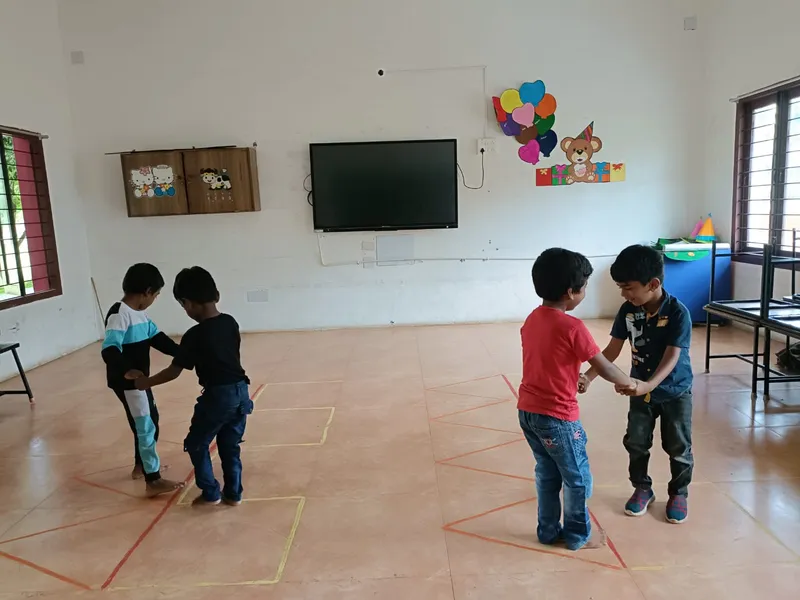 Children holding hands while navigating line patterns in the classroom.