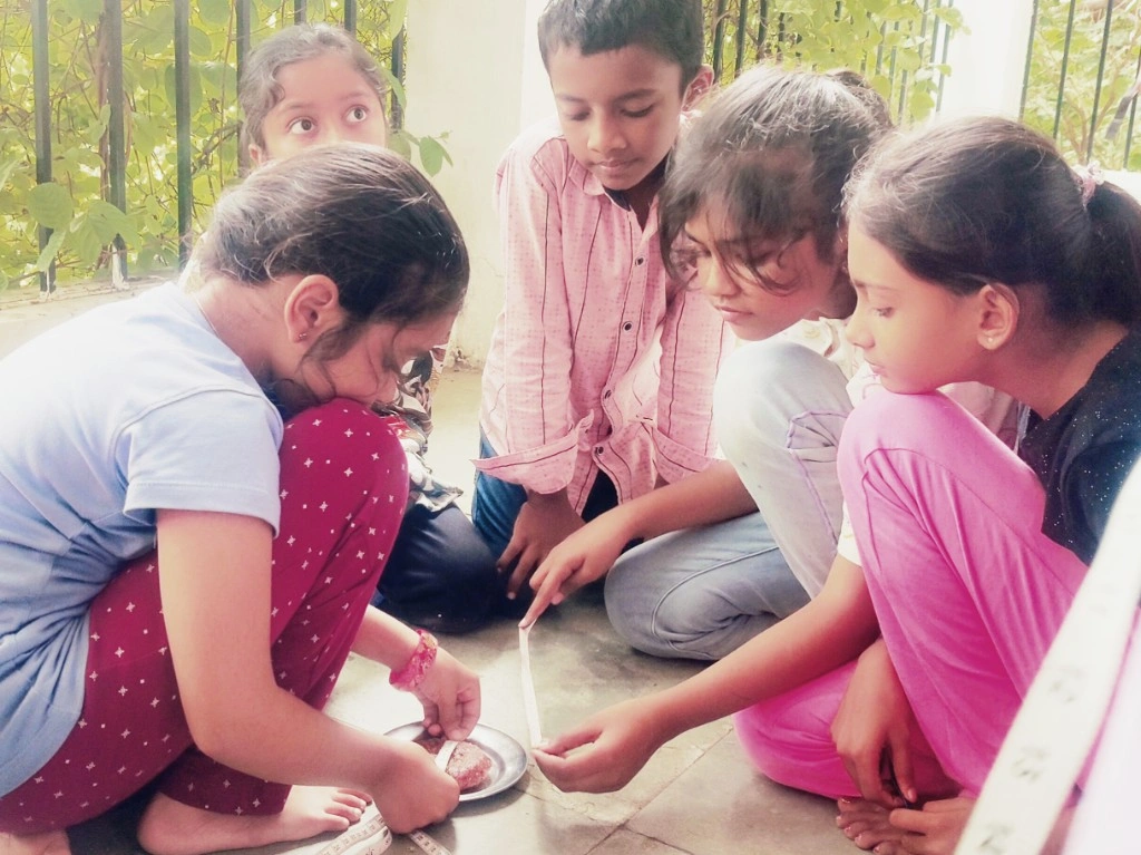 Group of children sitting outdoors, measuring real-life circle-shaped objects like plates for a math activity on radius and diameter
