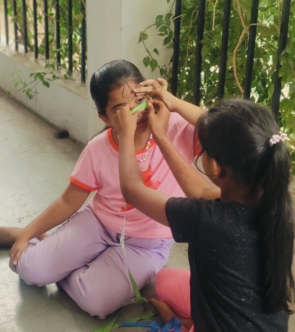 Two girls measuring the diameter of a student's eye during the radius and diameter link activity