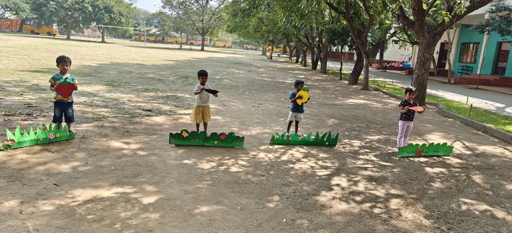 Young learners standing on custom-designed grass platforms during the fruit identification activity