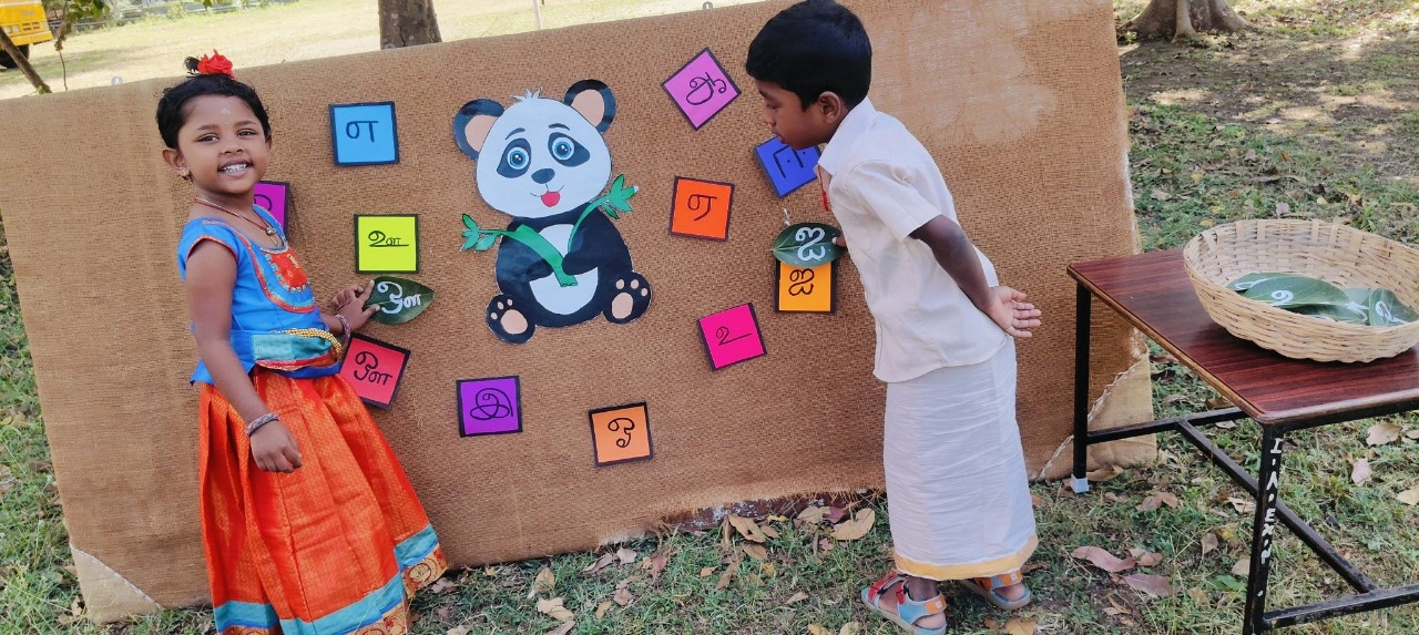 Students in colorful traditional wear participating in Tamil language learning game
