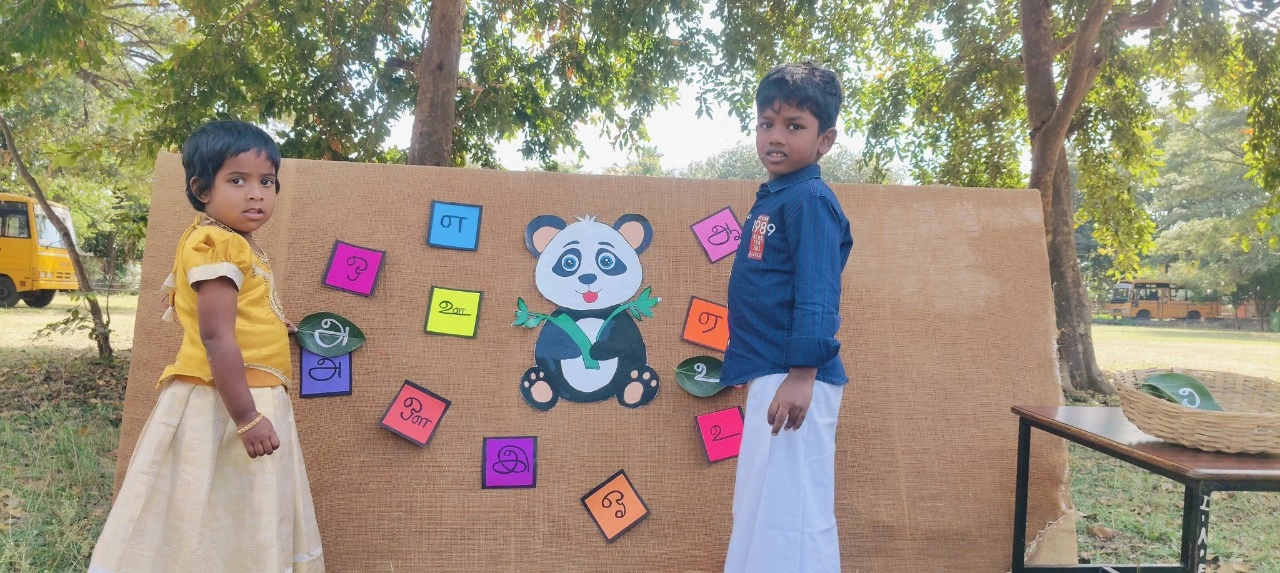 Children in traditional attire learning Tamil letters through interactive board activity