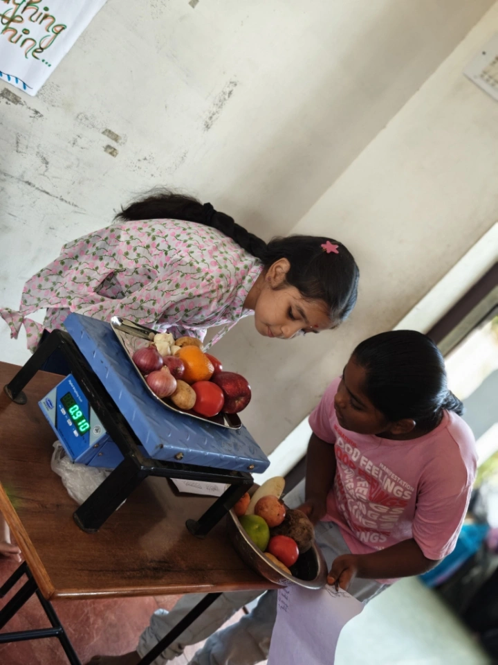 Students comparing weight measurements of fruits