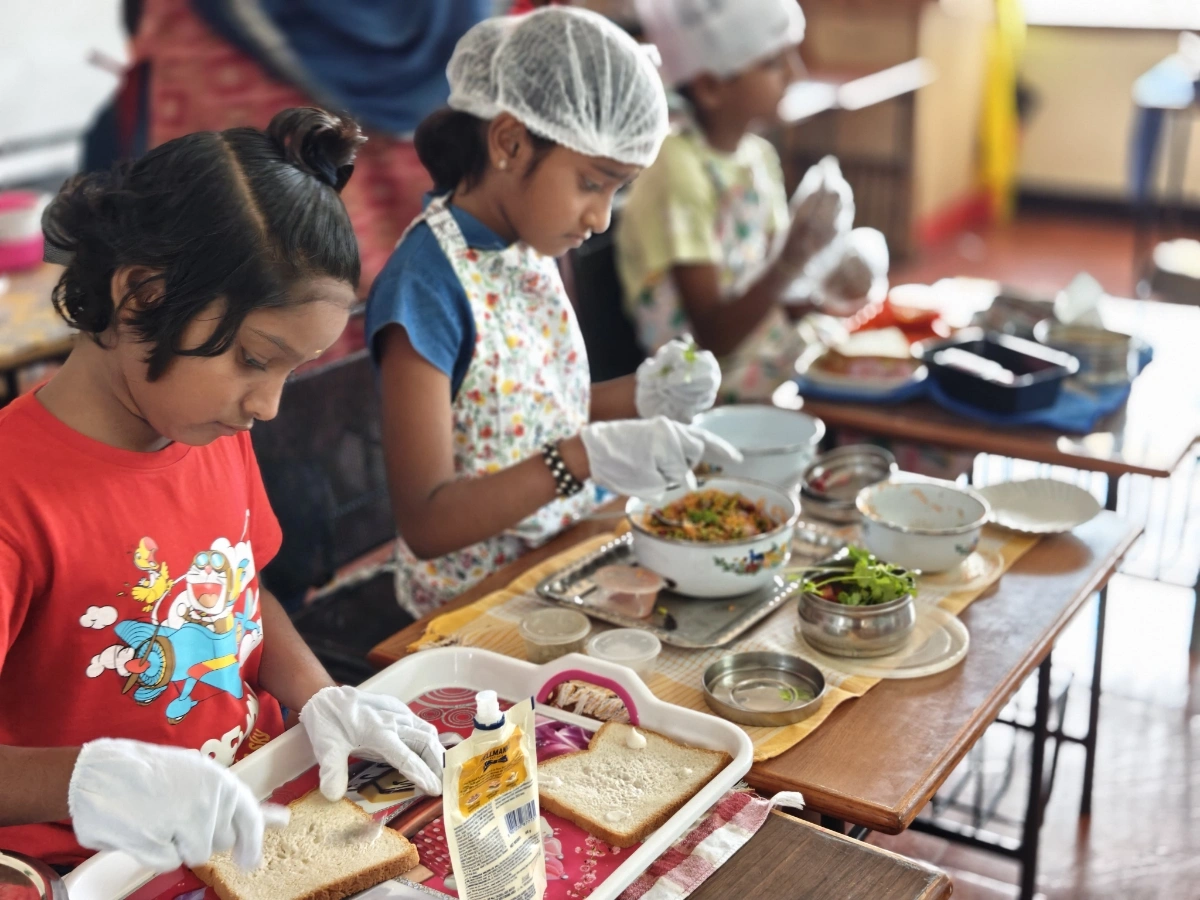 Students engaged in sandwich assembly showing attention to detail and hygiene