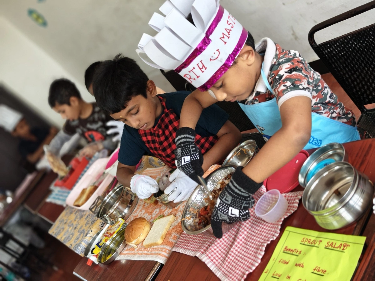Students focused on food preparation wearing hygiene caps and gloves in the cooking activity