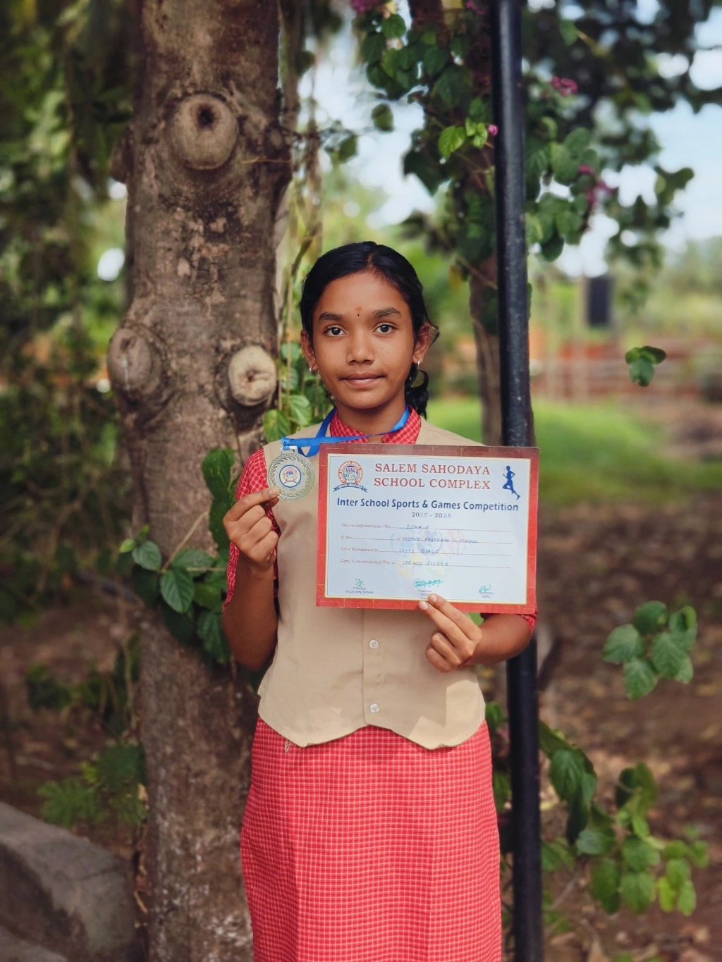 Grade 6 student Isha displaying silver medal certificate from Salem Sahodaya 100m running race at interschool sports competitions