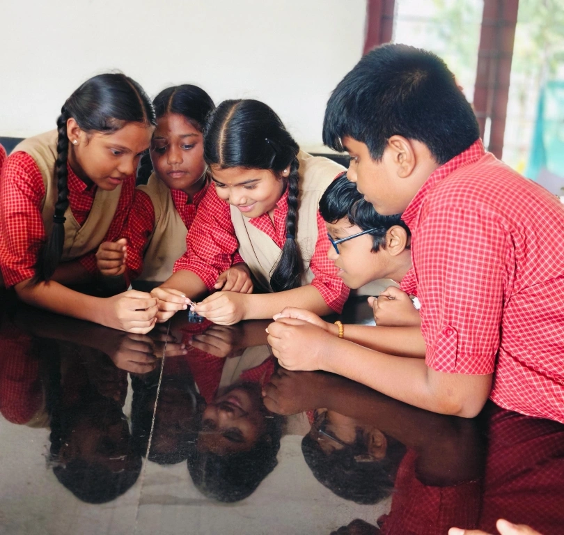 5th grade students building simple circuits with batteries and LED bulbs at Vidhya Peetham i-School Salem science lab